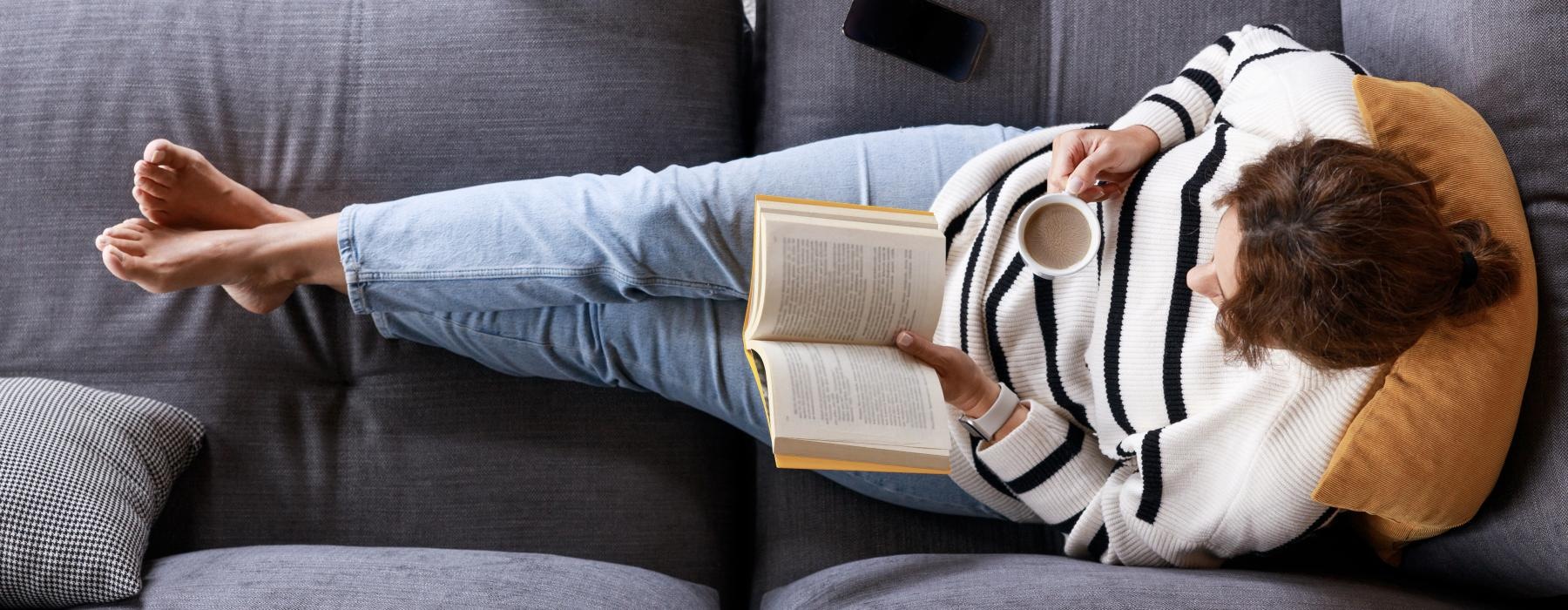 a person lying on a couch reading a book